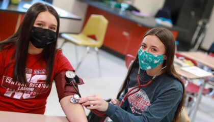 Two students; one is taking another's blood pressure