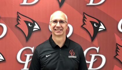 Dan Johnson, new Jr-Sr high principal stands in front of the red Central Decatur Cardinal logo.