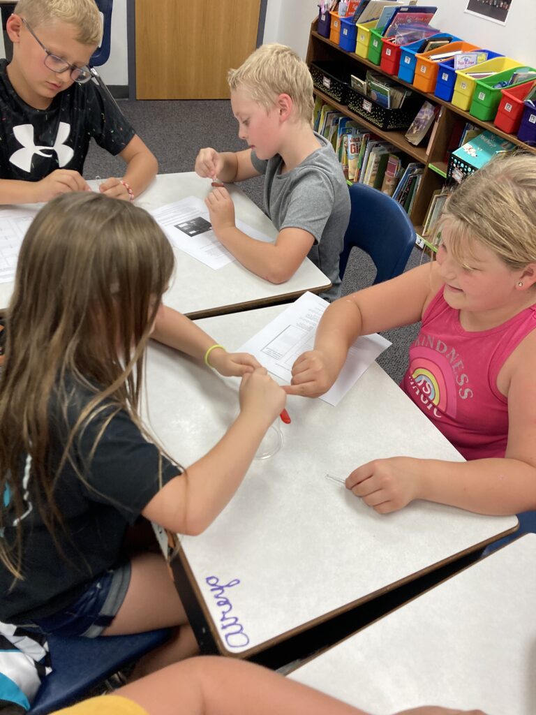 Third grade students work together to complete a teamwork activity.