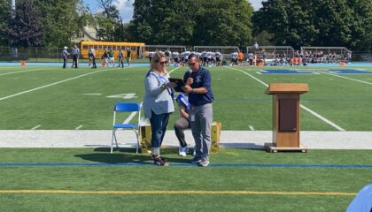 Kerry Welch receives her Hall of Fame plaque at a Hewlett High School football game.