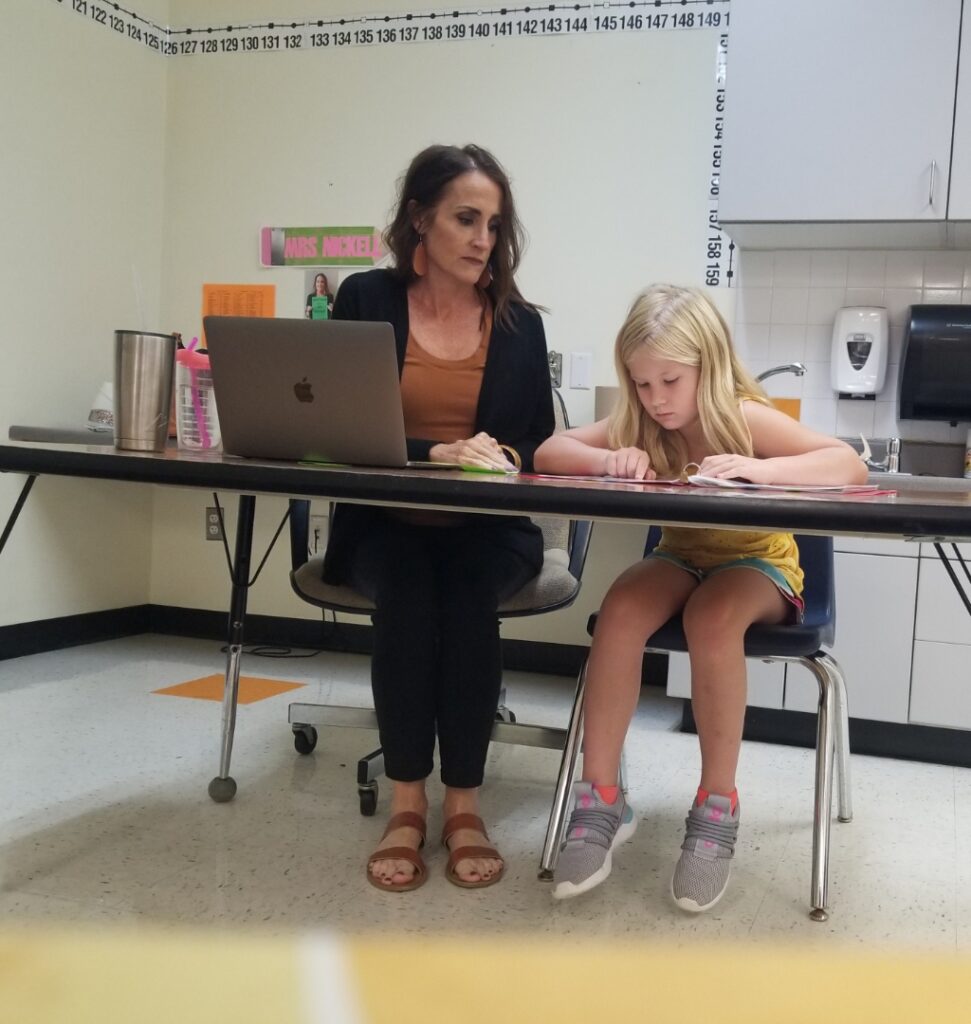 A teacher gives the FAST reading test to a student.