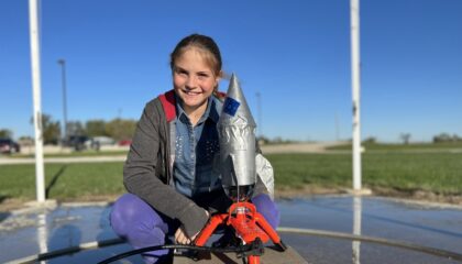 a sixth grader poses with a rocket just before launch