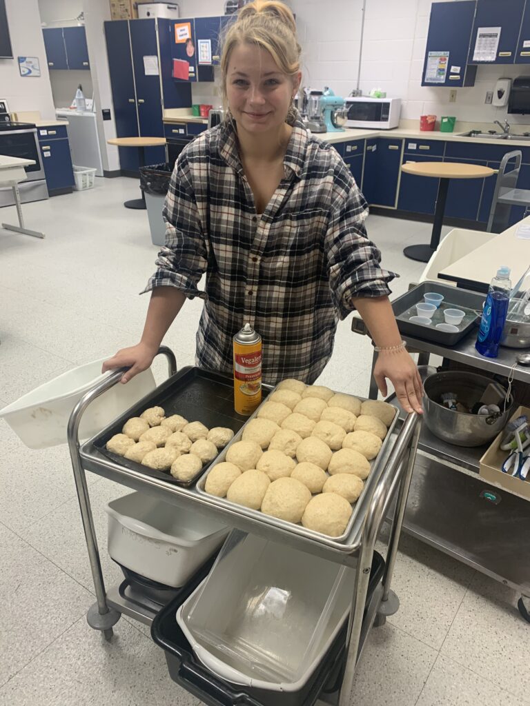 A culinary arts student shows the dinner rolls that will be baked for all music night.