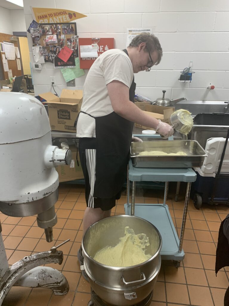 An advanced culinary arts student prepares dough for the all music night dinner rolls.