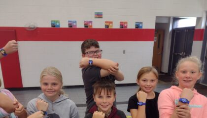 elementary PE students show their wrist worn heart rate monitors