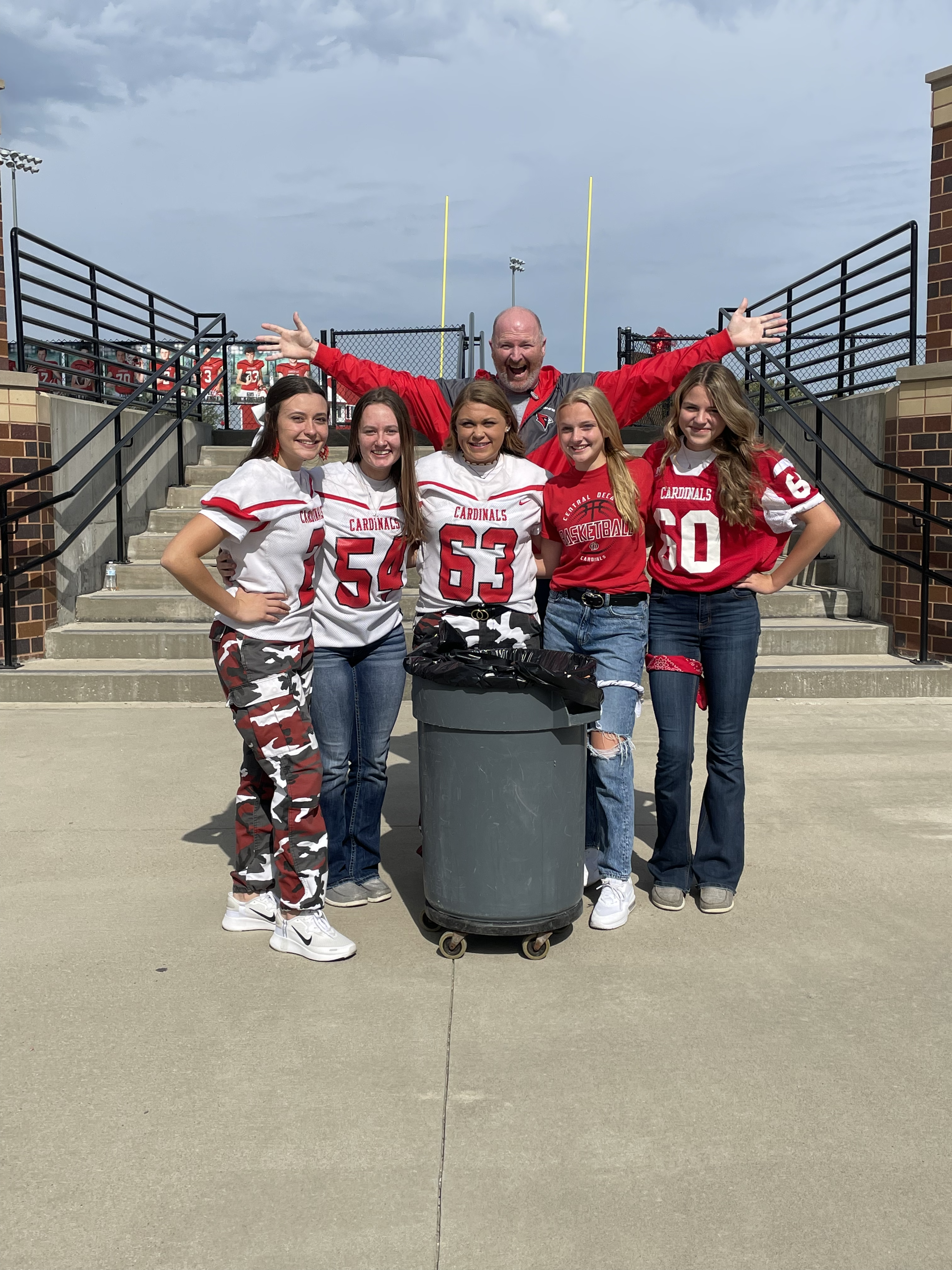 Five high school students gather around a trash can after being recognized for their RED way behavior