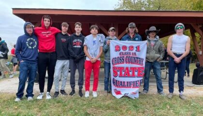 boys cross country team with state qualifying banner