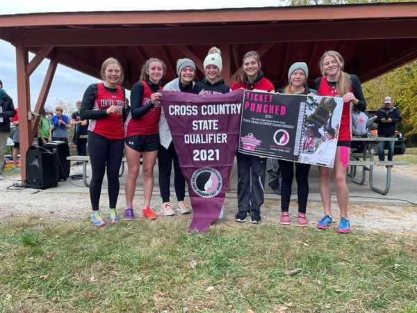 Girls cross country team with state qualifying banner