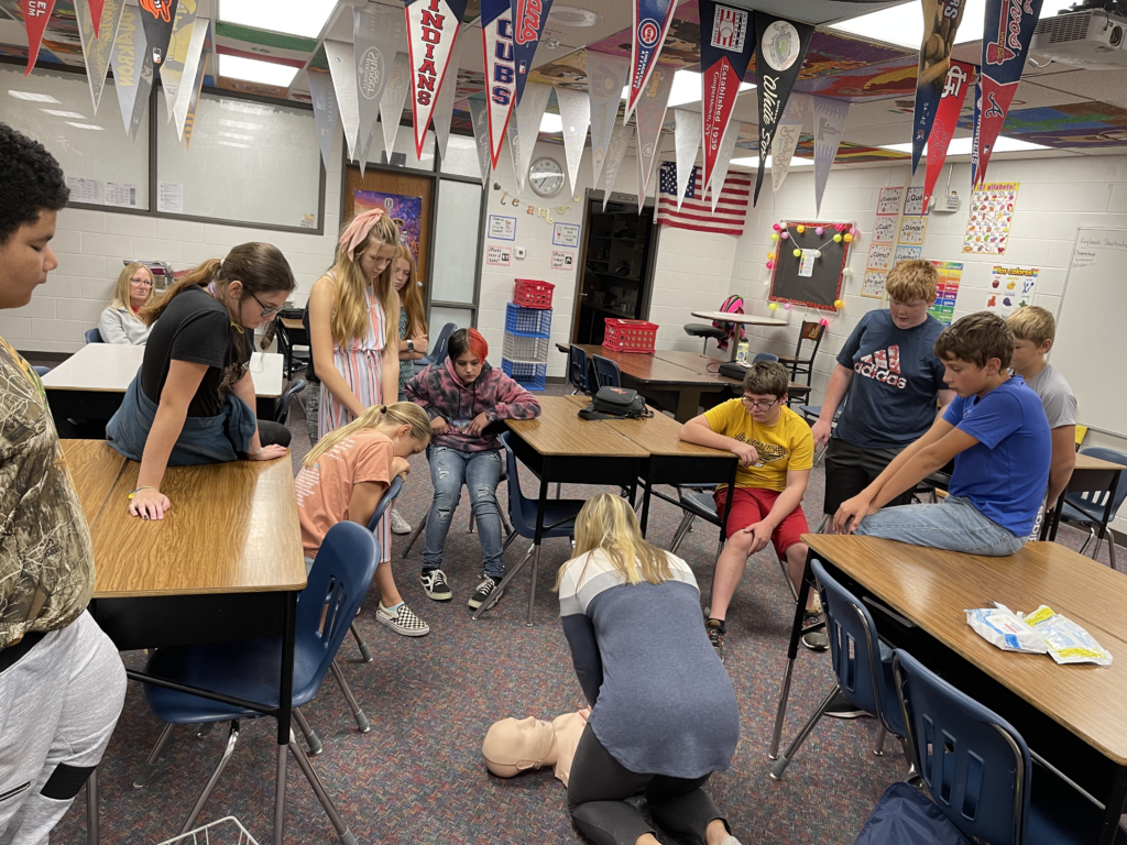 Health class learns CPR compressions from school nurse