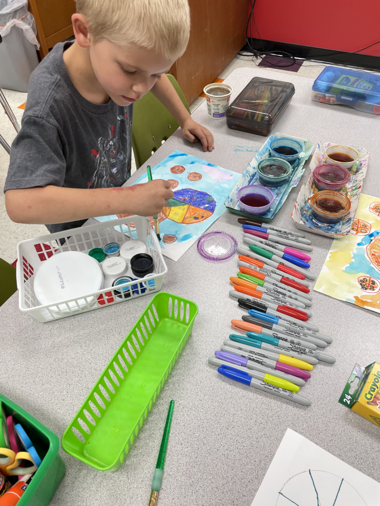 a second grade art student paints dots