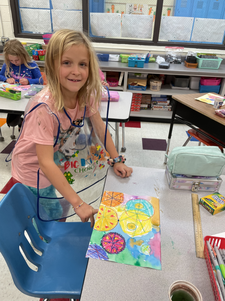 A second grade student finishes her painting.