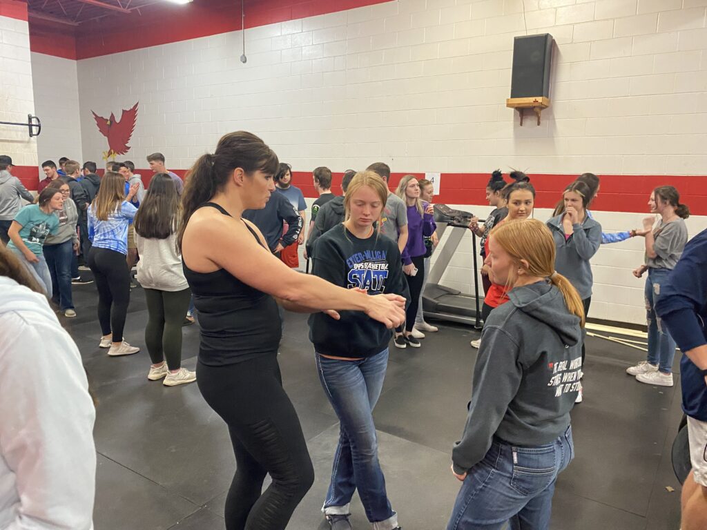 High school PE class learns self defense techniques from CD alum Stacy (Andrew) Purdom.