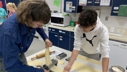 two students roll pasta dough in a step of making fresh pasta