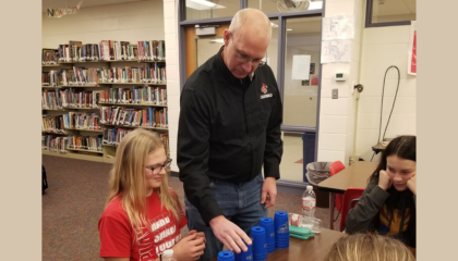 Secondary Principal, Mr. Johnson, challenges a student in a cup stacking contest.