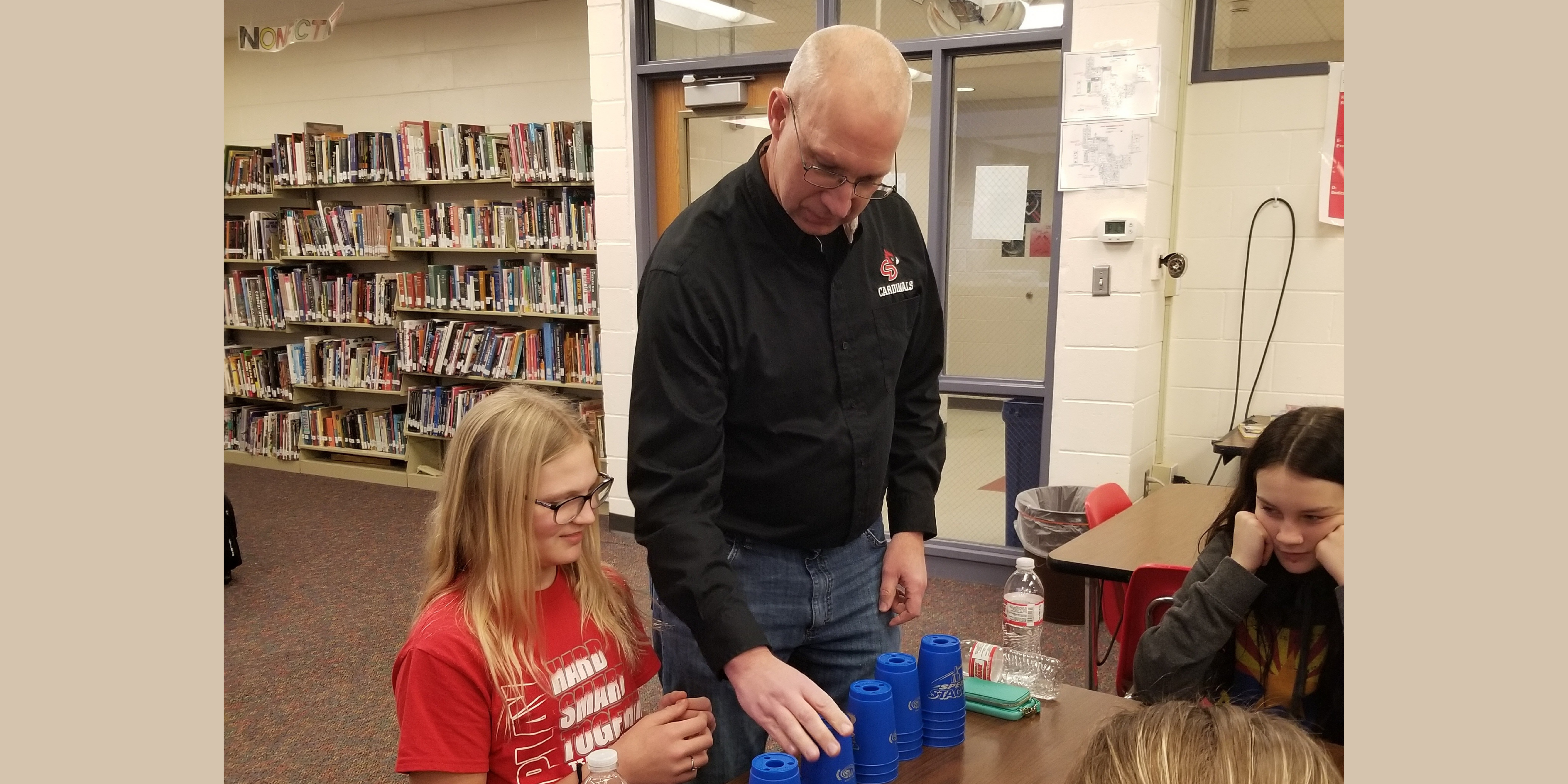 Secondary Principal, Mr. Johnson, challenges a student in a cup stacking contest.